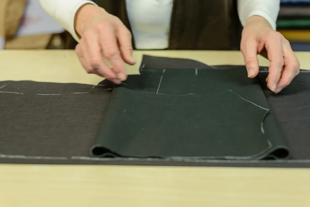 Hands laying out a cut pattern piece at Maßschneiderei Schwazer
