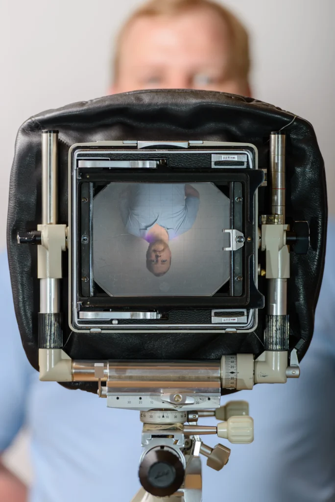 Simon Bailey, commercial photographer, reflected in the ground glass of a large format camera
