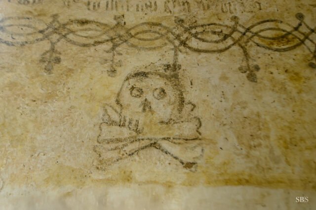 A skull and crossbones on the east wall of Llangelynnin Old Church, painted beneath the Ten Commandments in Welsh, near the altar. Date unknown.

The motif was common in medieval churches – a reminder of human mortality and the parts of the body required for resurrection.

Llangelynnin has been a place of worship for over nine centuries. It sits at 280m on the slopes of Tal y Fan above the Conwy valley, with no electricity, no heating, and no running water – @caruconwy hold a service on the third Sunday of every month during the summer. Full journal post – link in bio.