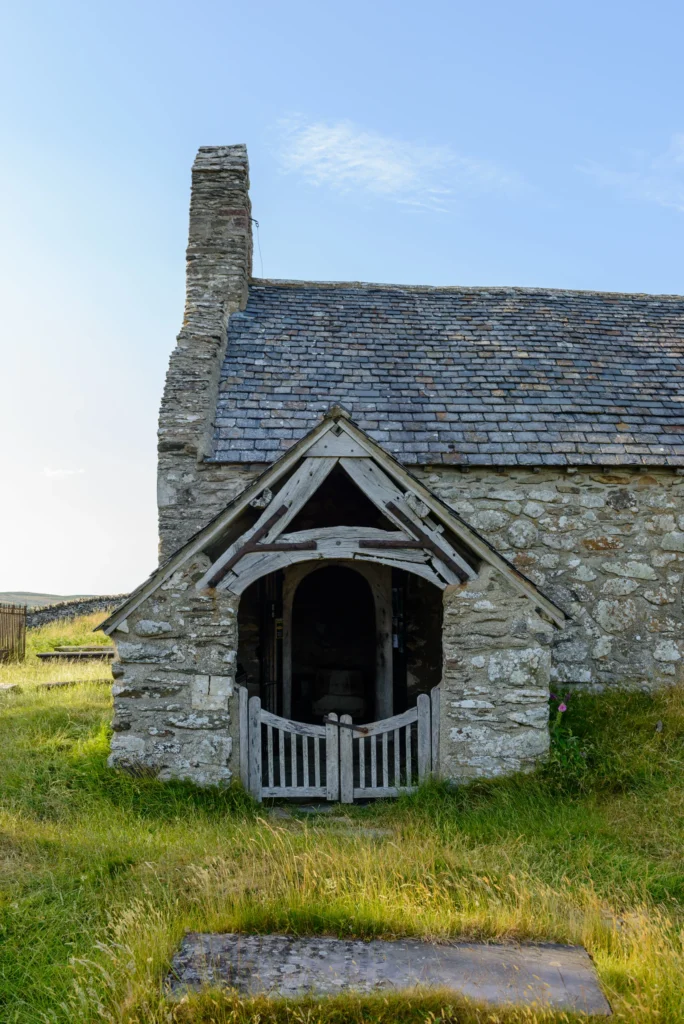 The stone south porch of Llangelynnin Old Church, with a simple wooden gate and rough-hewn stone archway.