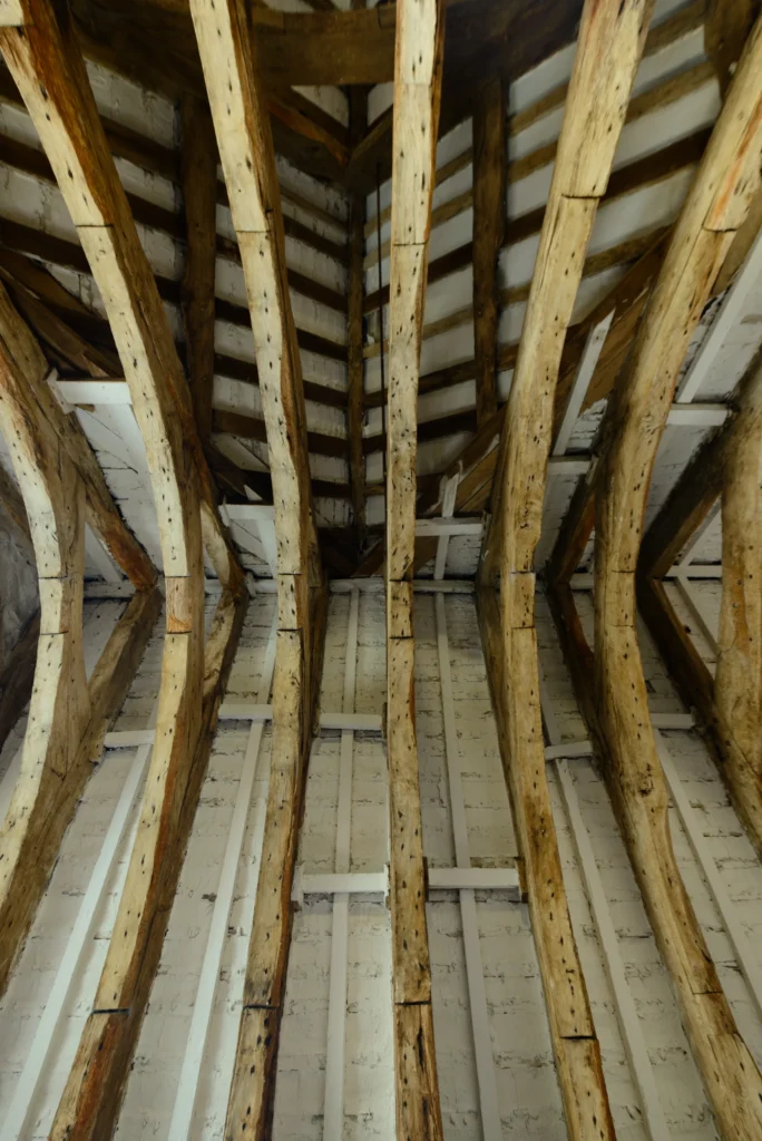 Looking up at dark oak roof timbers from the nave floor.