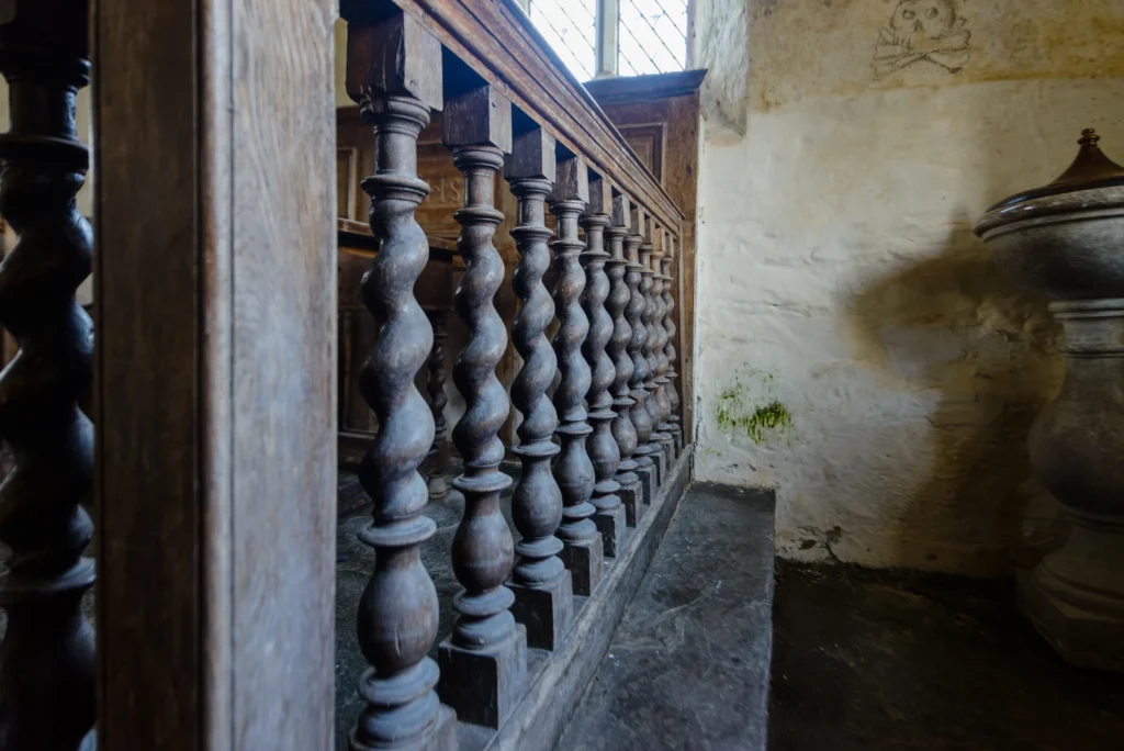 Seventeenth century altar rails in dark oak with turned balusters, separating nave from chancel.