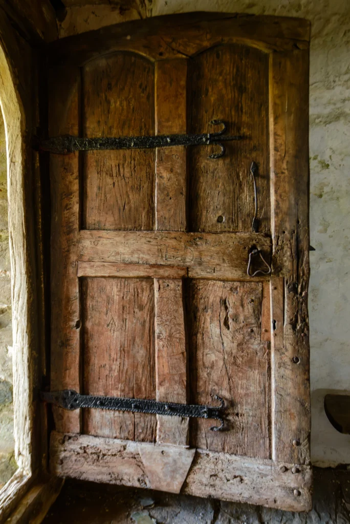 The south entrance door of Llangelynnin Old Church, heavy timber with 14th century strap hinges running across its width.