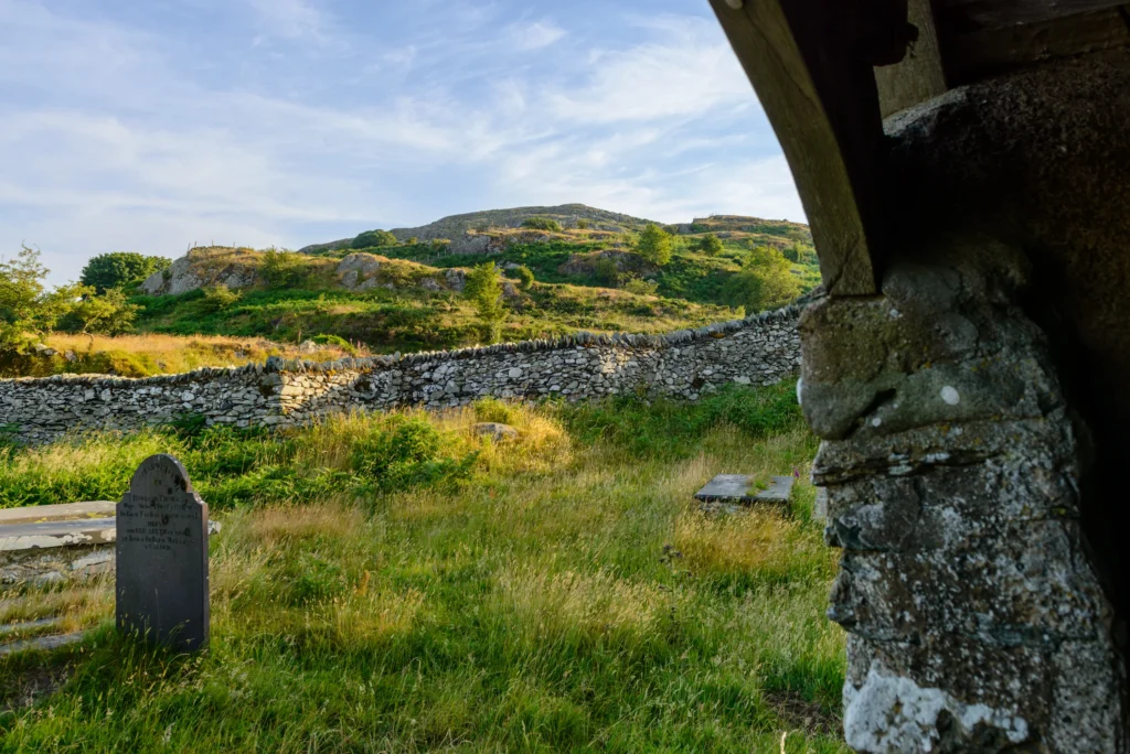 View south from the entrance porch toward Craig Celynin, with churchyard gravestones in the foreground.