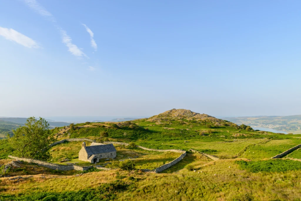 Llangelynnin Old Church and its oval churchyard seen from Craig Celynin, the Conwy estuary and hills beyond.