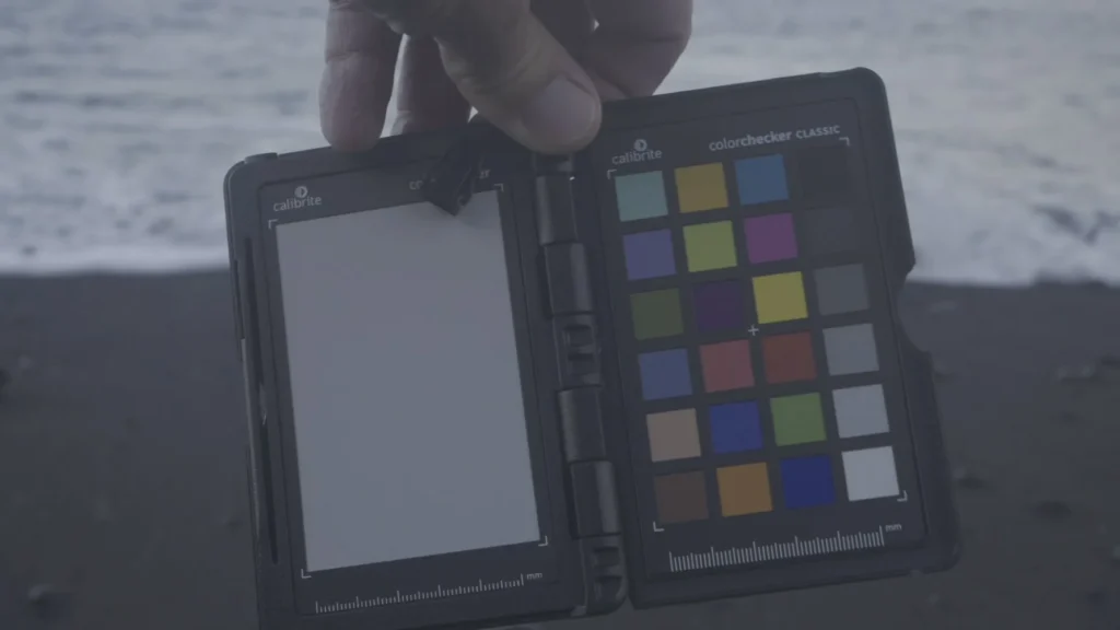 A colour checker in the early morning light in front of waves.